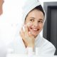 Woman looking at mirror and caring about her skin