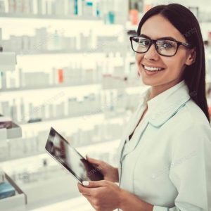 Female pharmacist using a digital tablet, looking at camera and smiling while working in pharmacy
