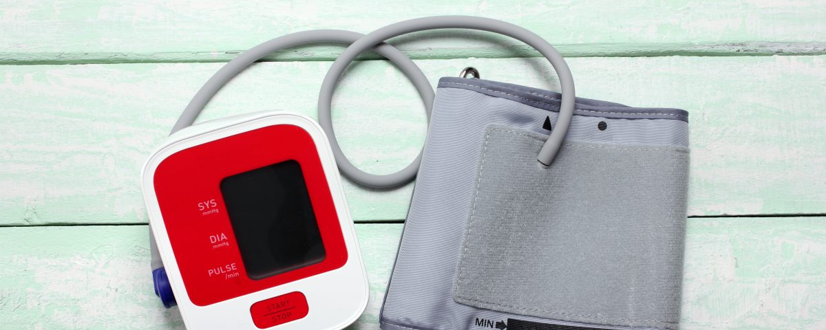 A medical device to monitor blood pressure for hypertension patient and medical cuff on a pistage wooden background