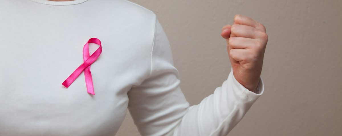 Girl in a white t-shirt with a pink ribbon on her breast fighting breast cancer