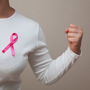 Girl in a white t-shirt with a pink ribbon on her breast fighting breast cancer
