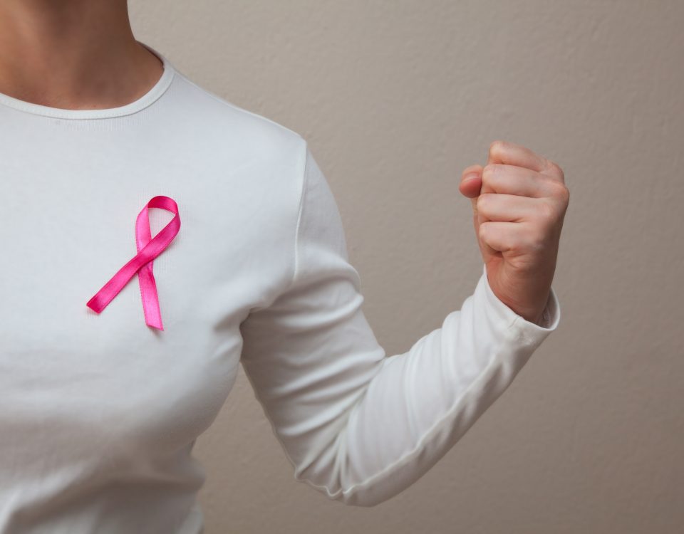 Girl in a white t-shirt with a pink ribbon on her breast fighting breast cancer