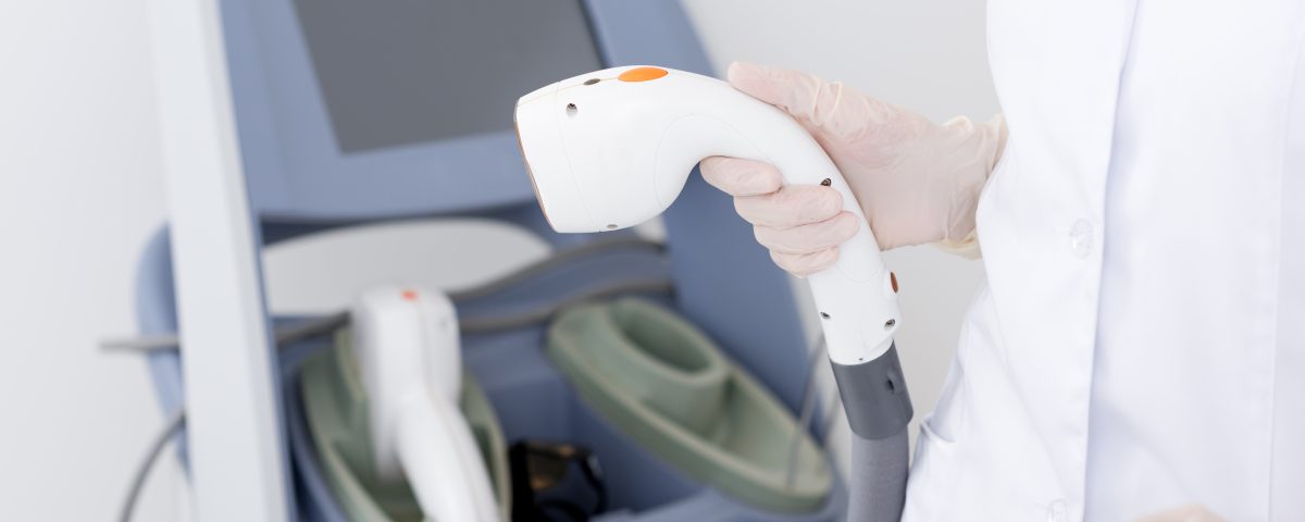cropped shot of dermatologist with laser hair removal apparatus preparing for the session in a clinic