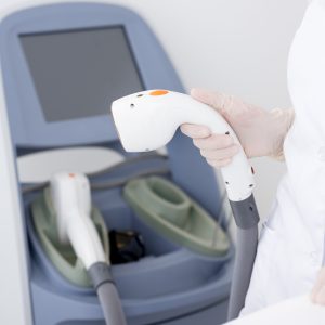 cropped shot of dermatologist with laser hair removal apparatus preparing for the session in a clinic