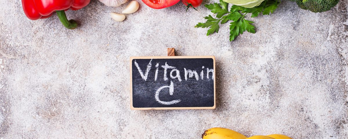 Vitamin C-written on a chalkboard next to vitamin C-containing foods