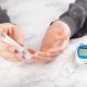 Diabetic patient using lancet on finger to check blood sugar or ketones level by glucose meter