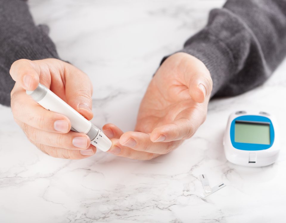Diabetic patient using lancet on finger to check blood sugar or ketones level by glucose meter