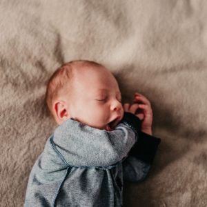Newborn suffering from jaundice yawns while sleeping on brown blanket