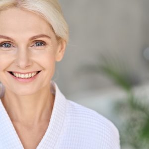 Portrait of smiling mid age woman with younger skin appearance looking at camera representing skin care and skin aging concepts.
