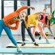 Group of smiling preteen kids wearing bright outfits and doing sport exercise together in a fitness class