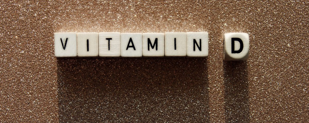 Wooden cubes with text vitamin D on a sandy background