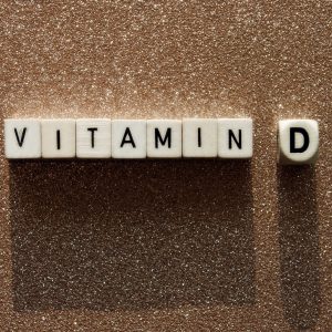 Wooden cubes with text vitamin D on a sandy background