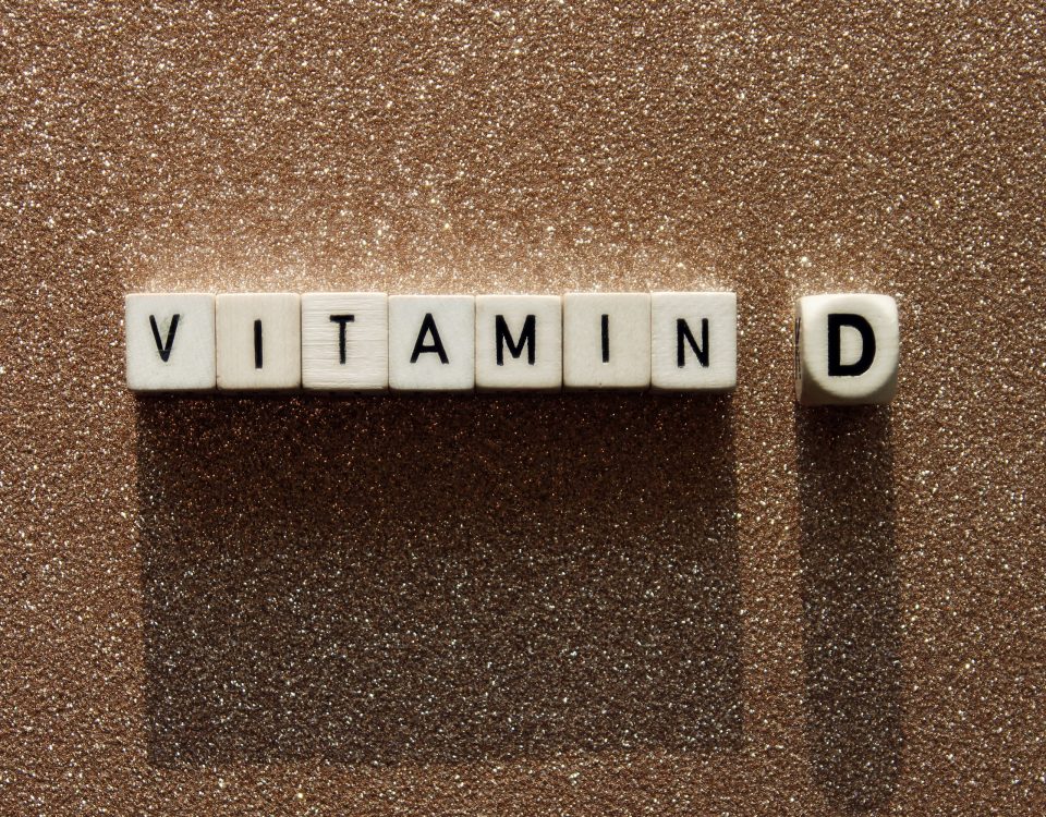 Wooden cubes with text vitamin D on a sandy background