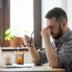 stressed man suffering massaging his nose bridge and suffering from headache
