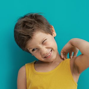 Boy wearing yellow shirt scratches his skin and suffers from atopic eczema