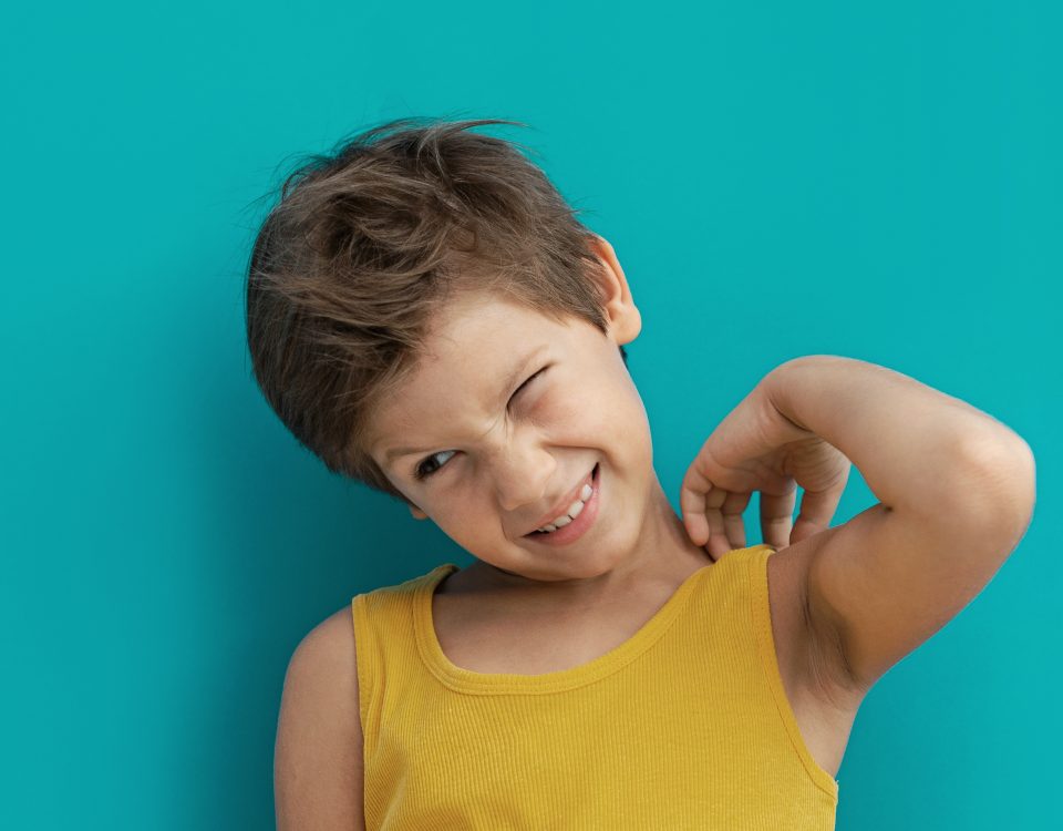 Boy wearing yellow shirt scratches his skin and suffers from atopic eczema