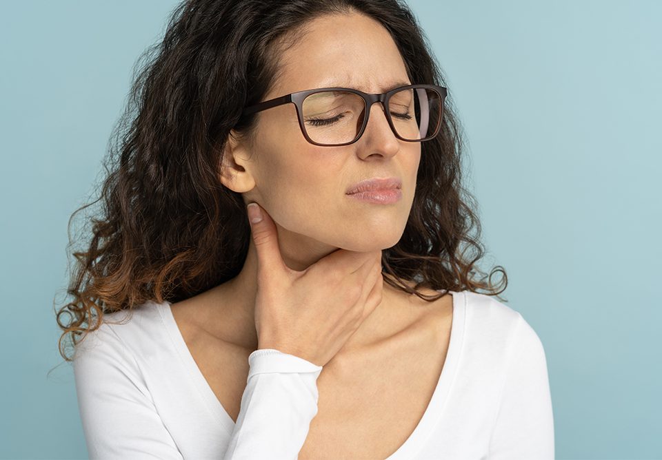 Sick woman wearing white blouse having sore throat on baby blue background
